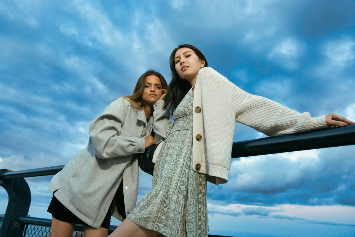 Two women posing against a cloudy sky