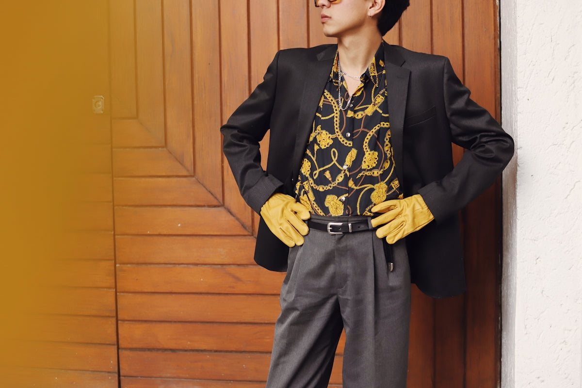 Man in stylish suit and gloves poses confidently.