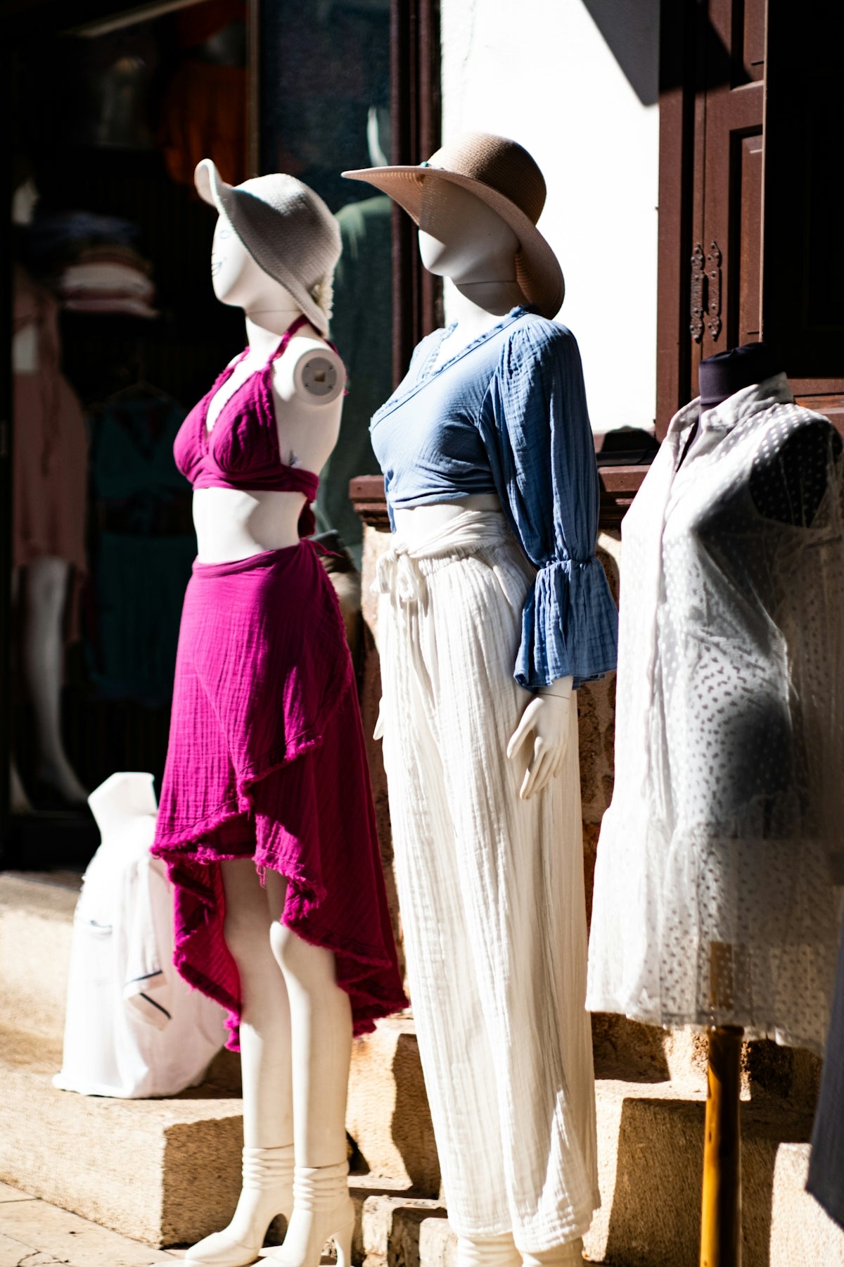 Mannequins in stylish summer outfits displayed outside.