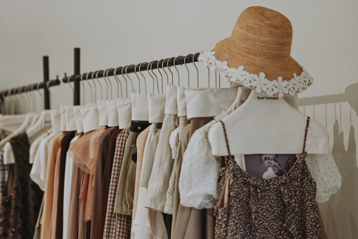 Clothes and straw hat on a clothing rack