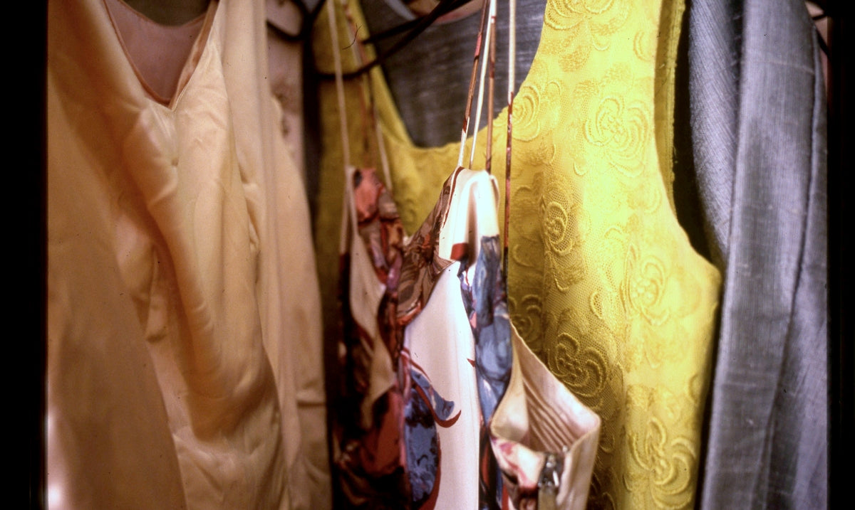 Various colorful clothes and patterned scarves hanging in a closet.