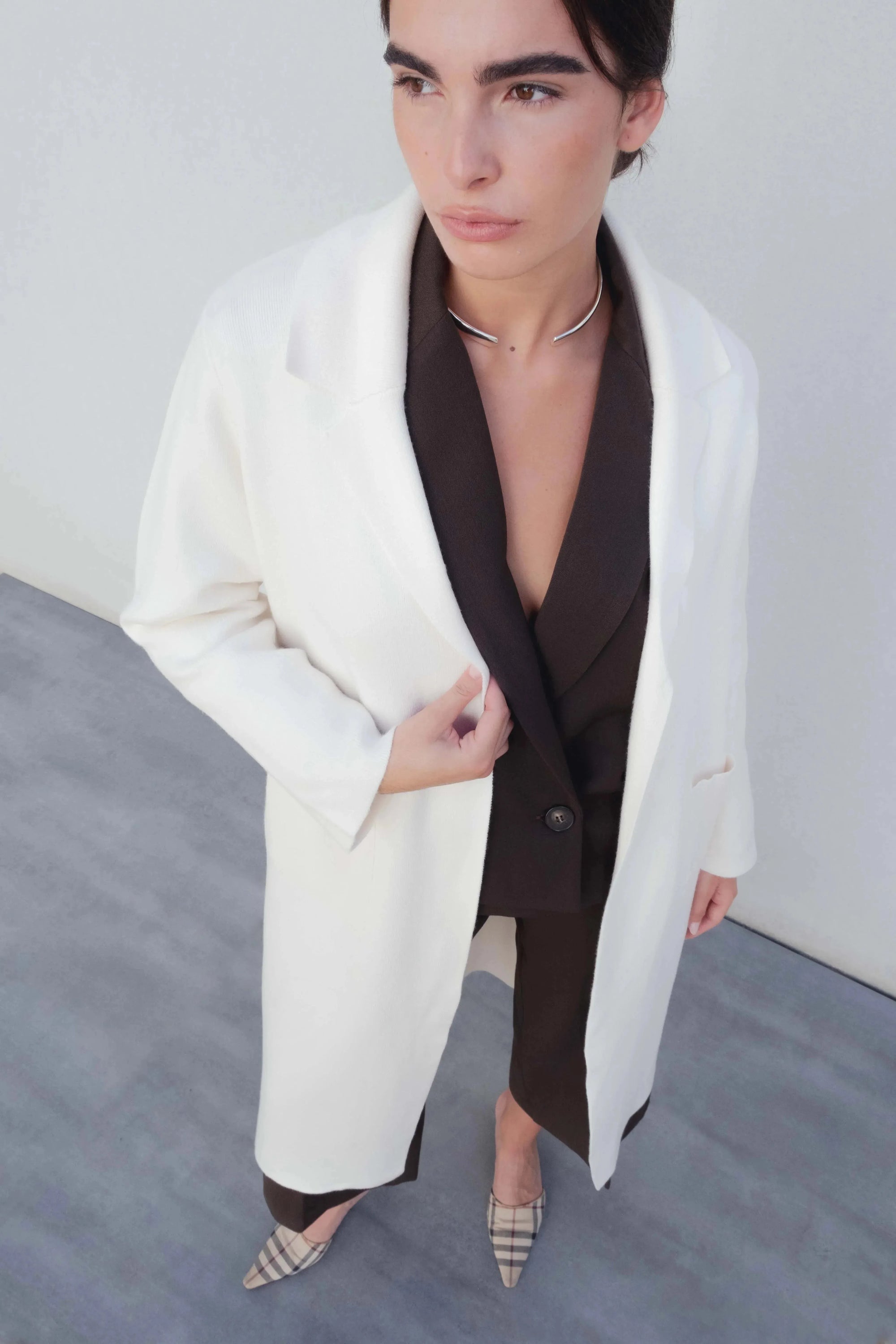 Manteaux pour femmes : Manteau beige à double boutonnage porté par une femme, offrant élégance et confort, idéal pour les occasions mi-saison.