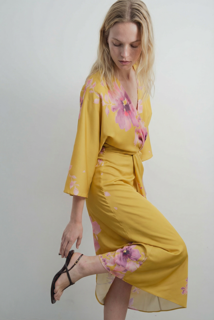 Vue de côté d'une robe midi satinée jaune à motifs floraux roses, col V et manches larges
