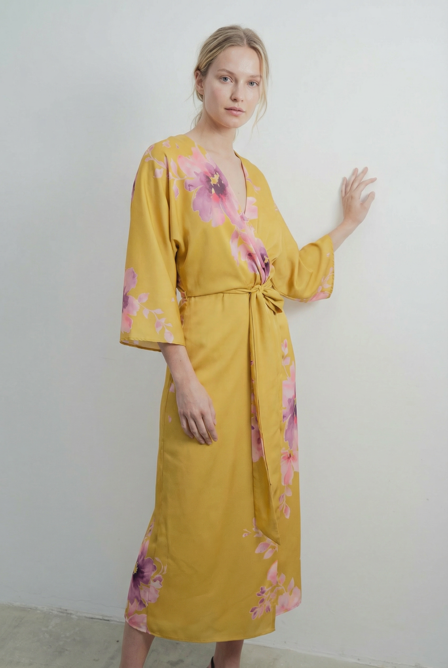 Vue de trois-quarts d'une robe midi croisée satinée jaune imprimée de fleurs roses