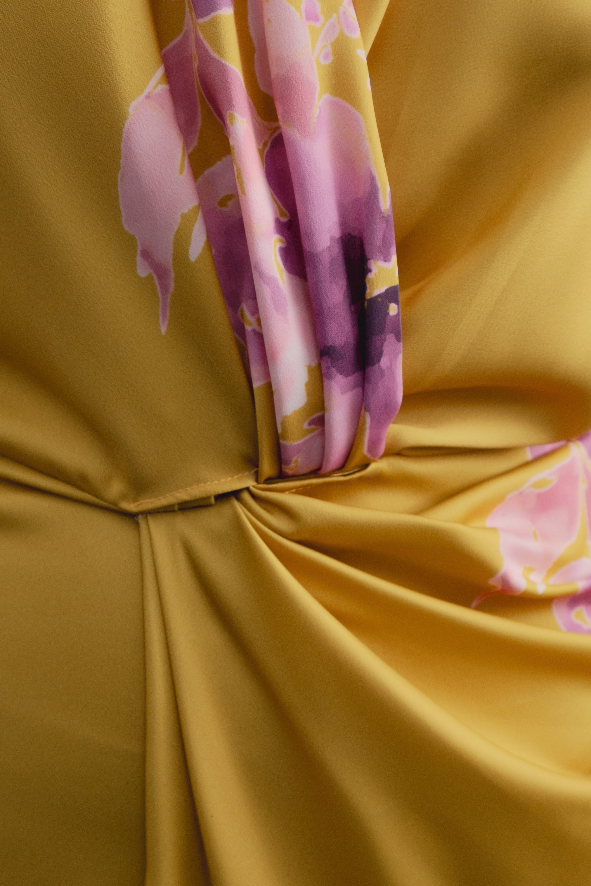 Gros plan sur la matière satinée jaune à motif floral rose et détail du drapé et du croisé