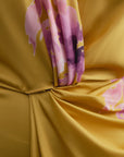 Gros plan sur la matière satinée jaune à motif floral rose et détail du drapé et du croisé