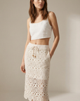 Femme portant une jupe en dentelle crème en coton taille haute élégante avec un haut en lin, parfait pour un look décontracté et chic.