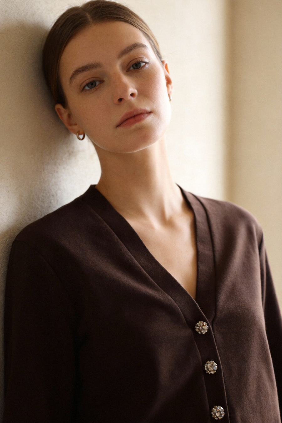 Portrait d'une femme portant un ensemble deux pièces coton femme en marron, mettant en avant la veste à col V et les détails des boutons.