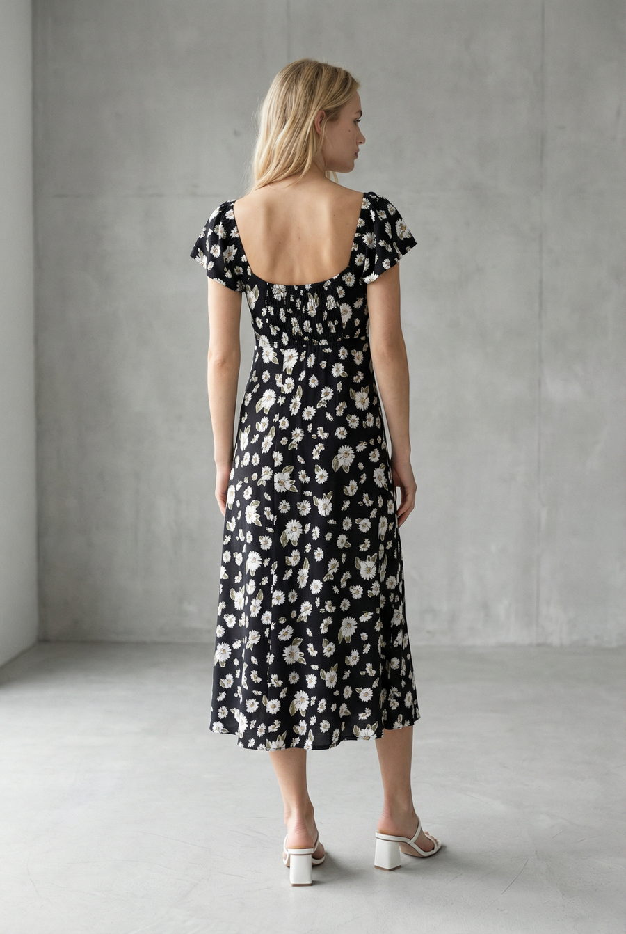 Femme de dos en robe longue noire à imprimé floral fendue sur le côté élégante, parfait pour compléter un look d'été avec la robe avec fente latérale.