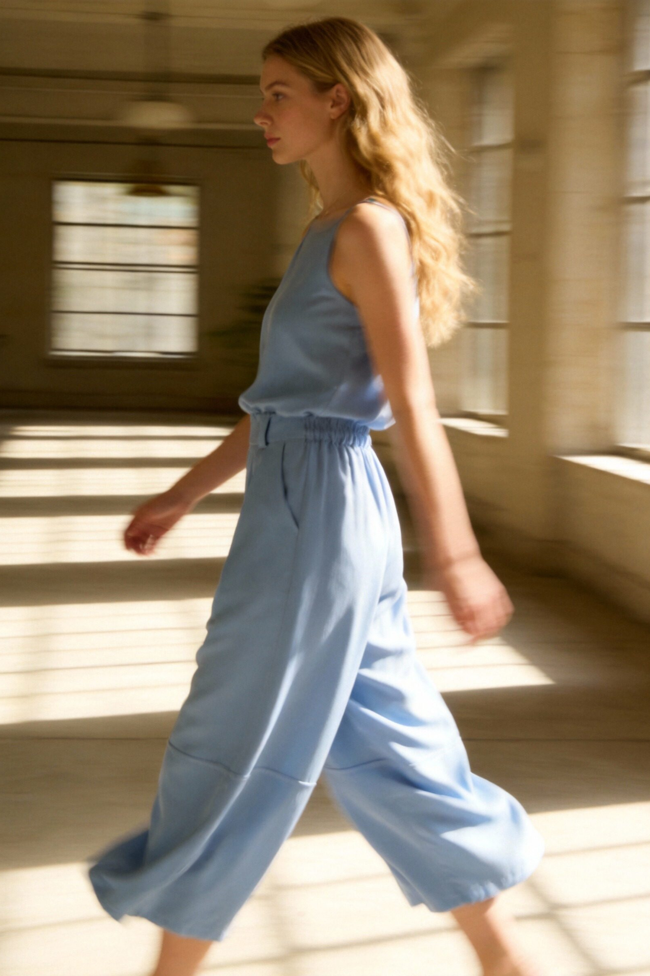 Modèle portant un pantalon court plissé taille haute ceinture élastique à poches, déambulant dans un environnement lumineux, parfait pour un look décontracté. Pantalon plissé femme.