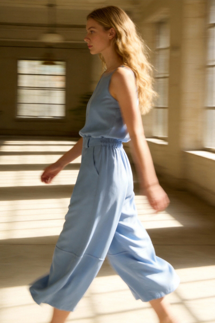 Modèle portant un pantalon court plissé taille haute ceinture élastique à poches, déambulant dans un environnement lumineux, parfait pour un look décontracté. Pantalon plissé femme.