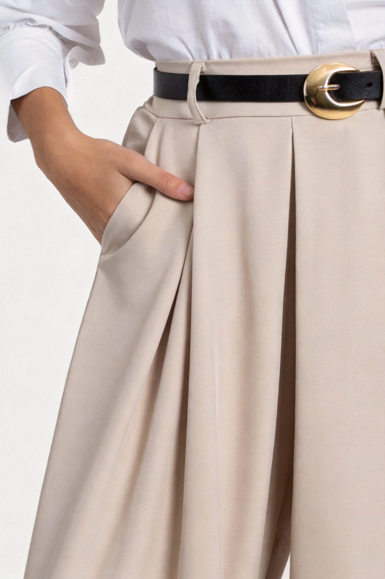 Détail du pantalon fluide taille haute femme en beige, avec une chemise blanche, présentant des plis élégants et une ceinture stylée.