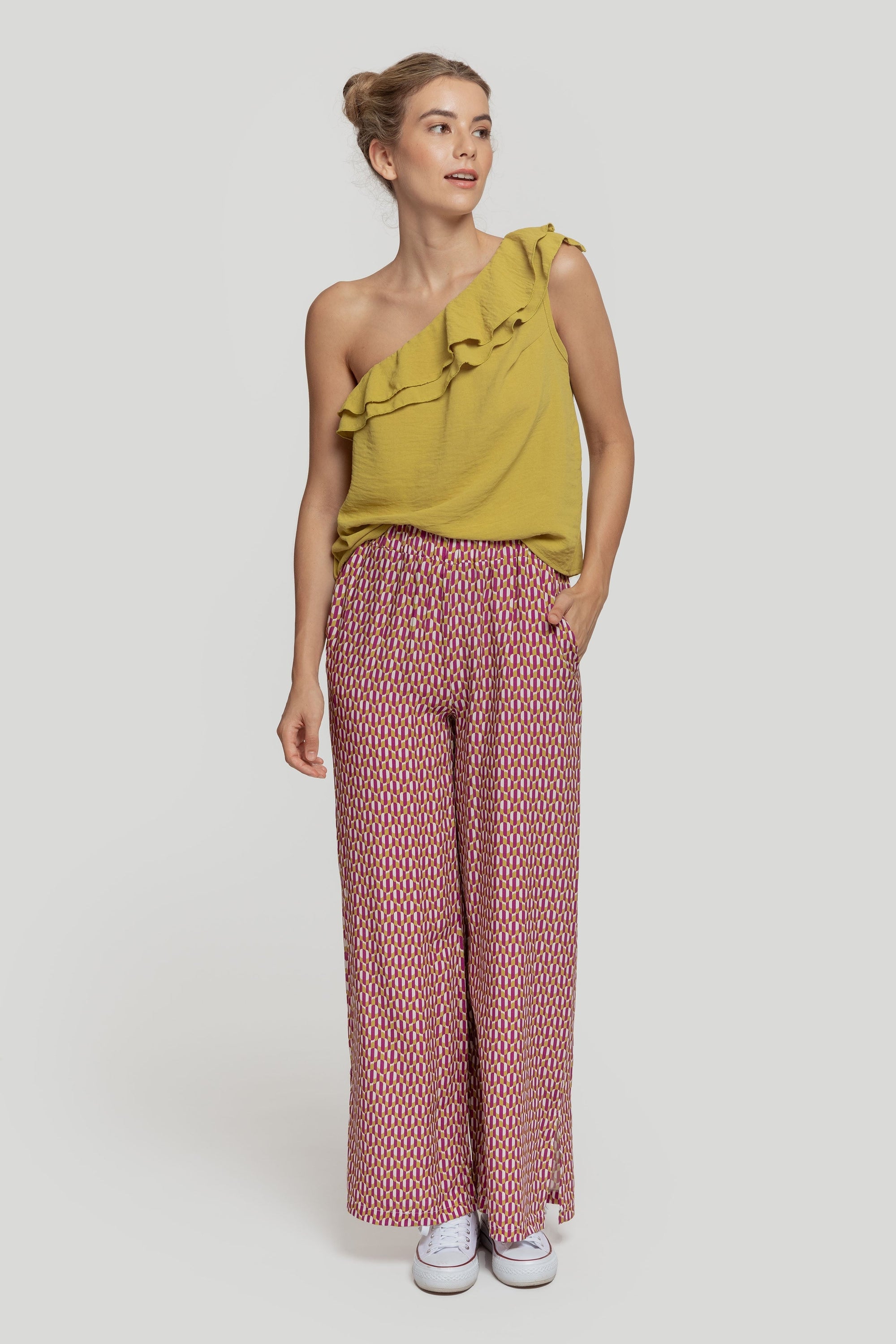 Femme souriante en pantalon droit taille haute en viscose avec un top asymétrique, démontrant le look élégant du pantalon taille haute femme.
