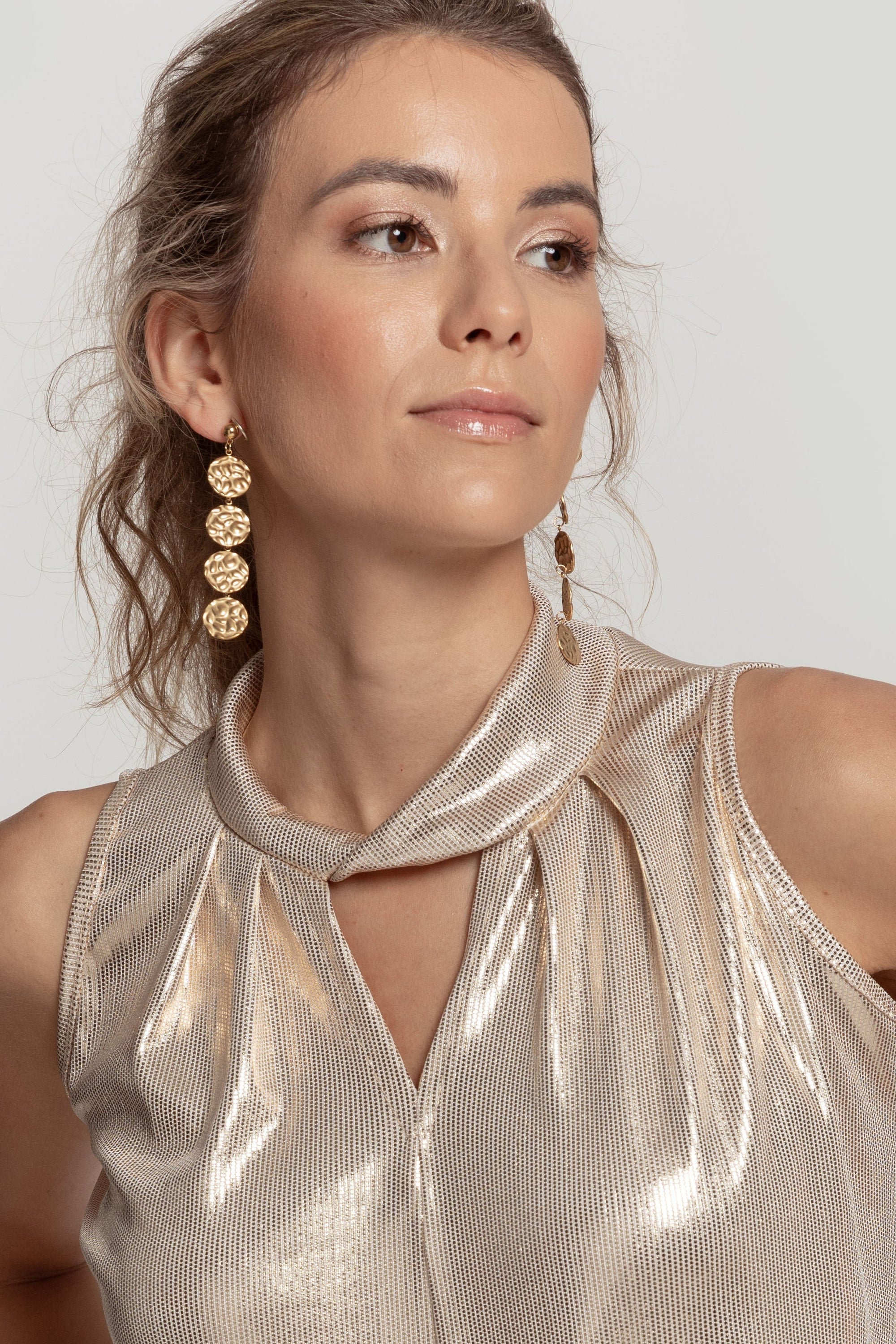 Femme portant des boucles d'oreilles pendantes dorées élégantes en acier inoxydable, ajoutant une touche chic à sa tenue.