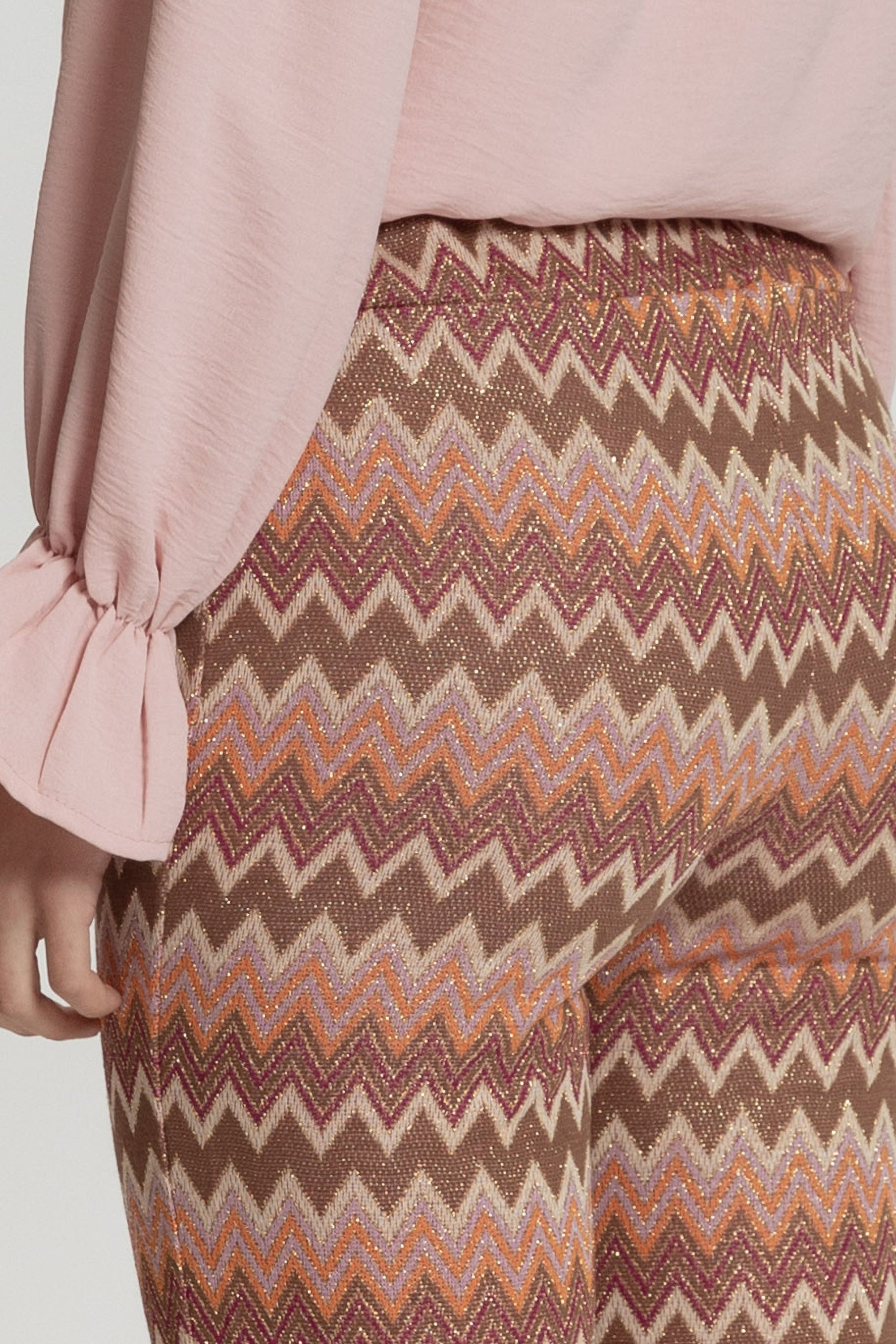 Pantalon flare taille haute femme porté avec une blouse satinée, parfait pour une tenue de soirée chic.