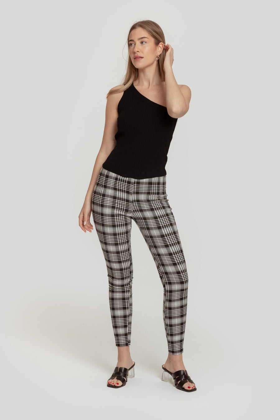Modèle portant un pantalon slim imprimé femme noir à taille élastique, associée à un top à une épaule, pour un look moderne et élégant.