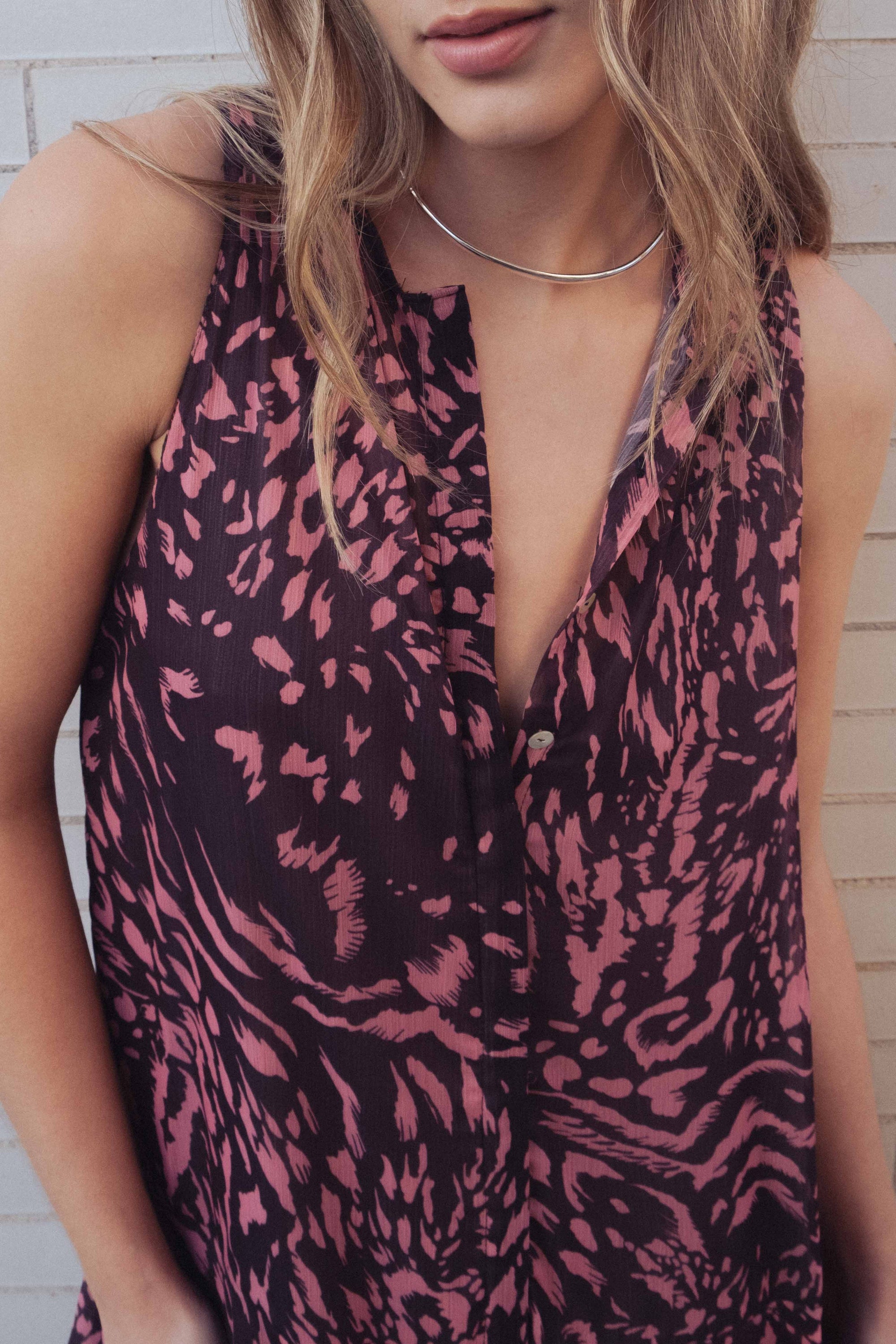 Robe longue imprimée à volants sans manches marron, femme se promenant en pleine lumière, style estival.