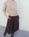 Bermuda long à pinces coupe droite marron coton stretch porté avec un pull beige, mettant en avant un look élégant et décontracté parfait pour les bermuda large femme ou bermuda femme long.