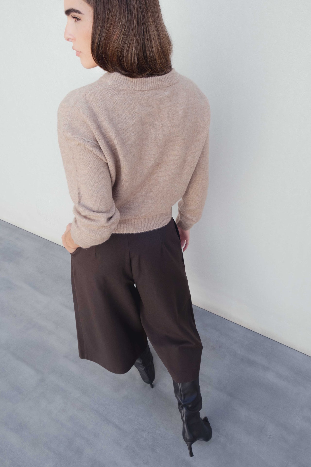 Vue arrière du Bermuda long à pinces coupe droite marron coton stretch porté avec un pull beige, illustrant le style moderne du bermuda large femme et bermuda femme long.