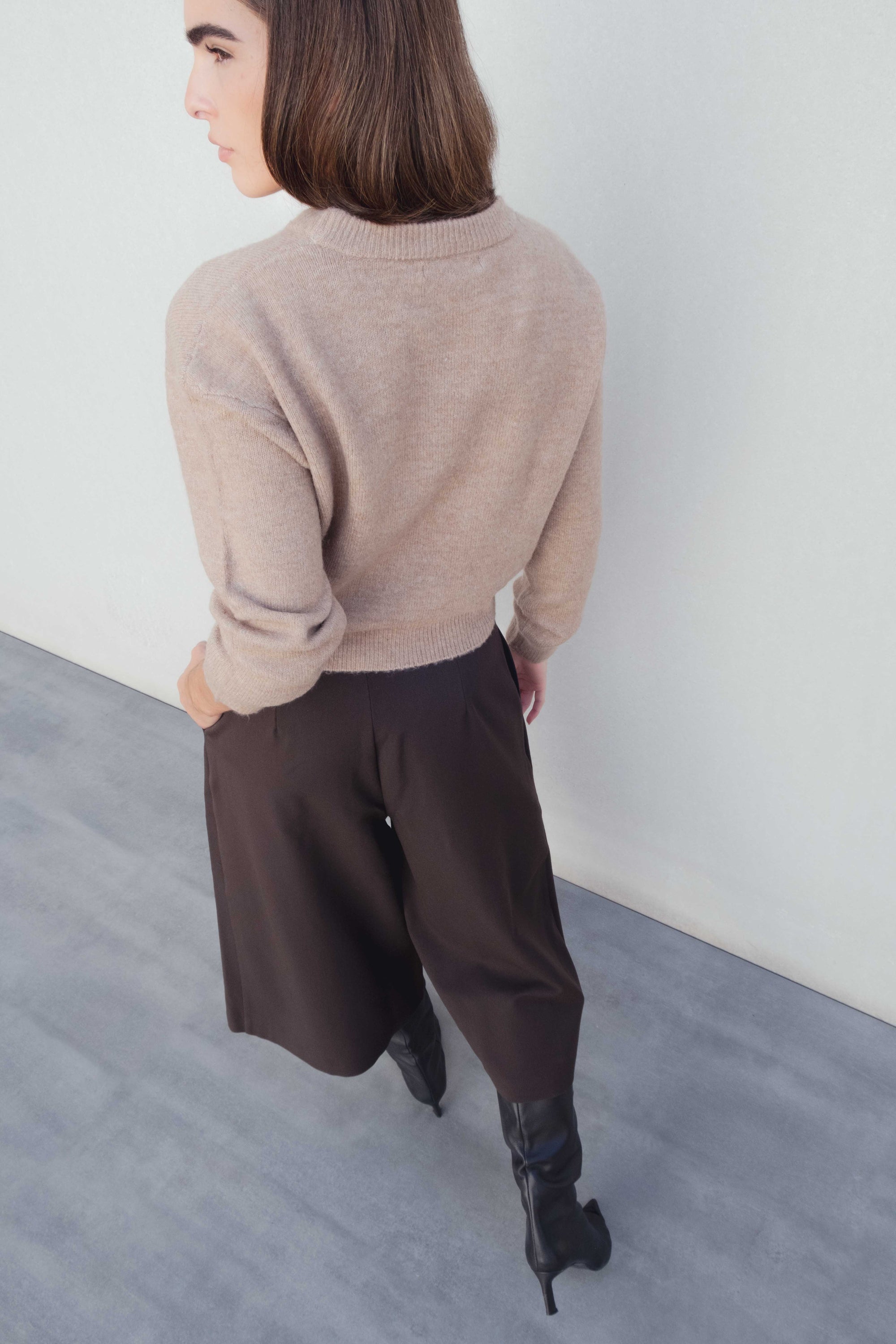 Vue arrière du Bermuda long à pinces coupe droite marron coton stretch porté avec un pull beige, illustrant le style moderne du bermuda large femme et bermuda femme long.