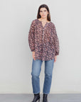 Femme présentant une blouse semi-transparente noire à fleurs, associée à un jean, parfaite pour un look casual. Blouse fleurie femme.