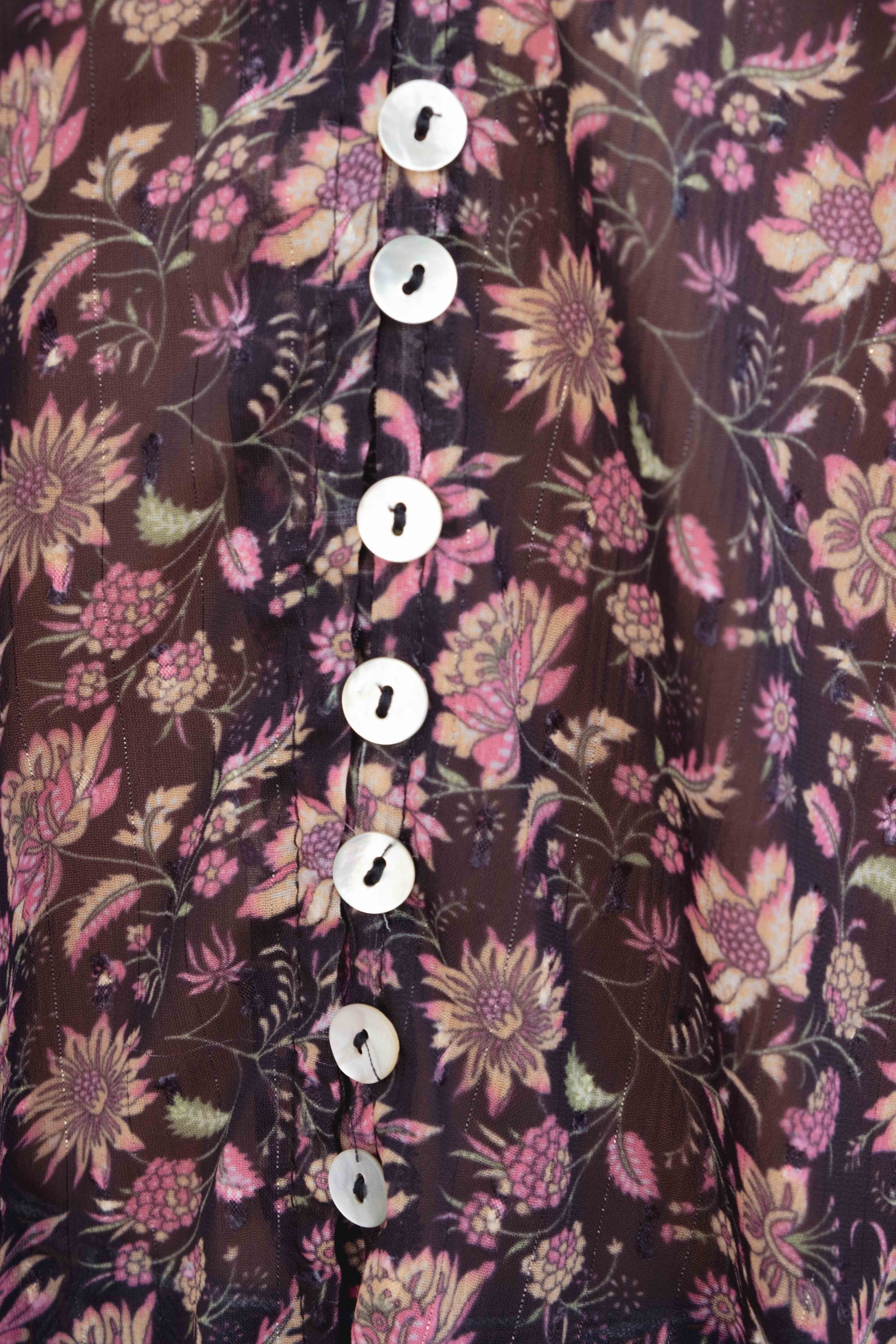 Gros plan sur les boutons d'une blouse semi-transparente noire avec imprimé floral, illustrant le design soigné de cette blouse. Blouse fleurie femme.