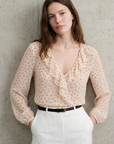 Blouse à volants pois écru devant mur