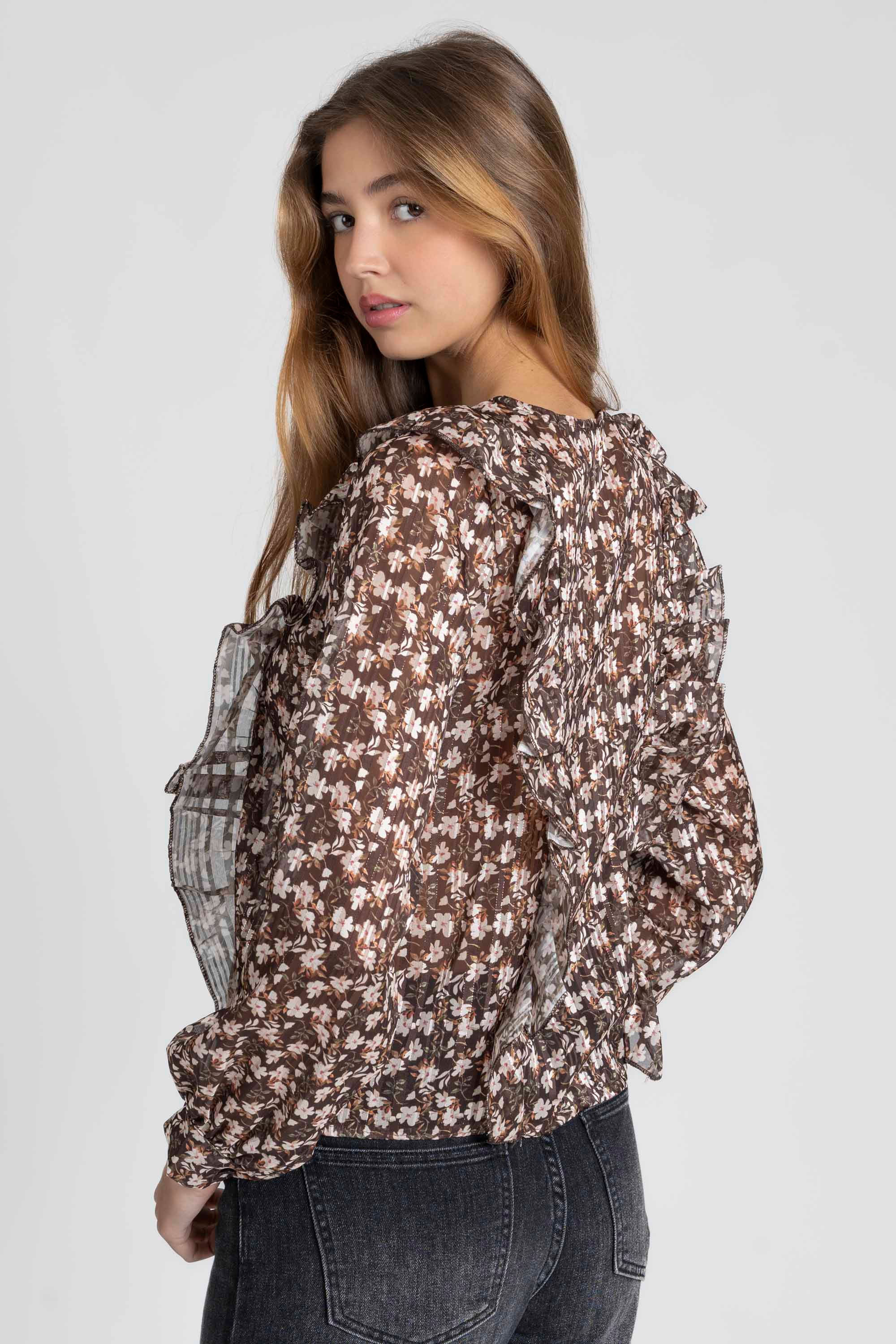 Vue arrière d'une femme en blouse fluide imprimé floral brillante, mettant en avant les volants aux épaules.