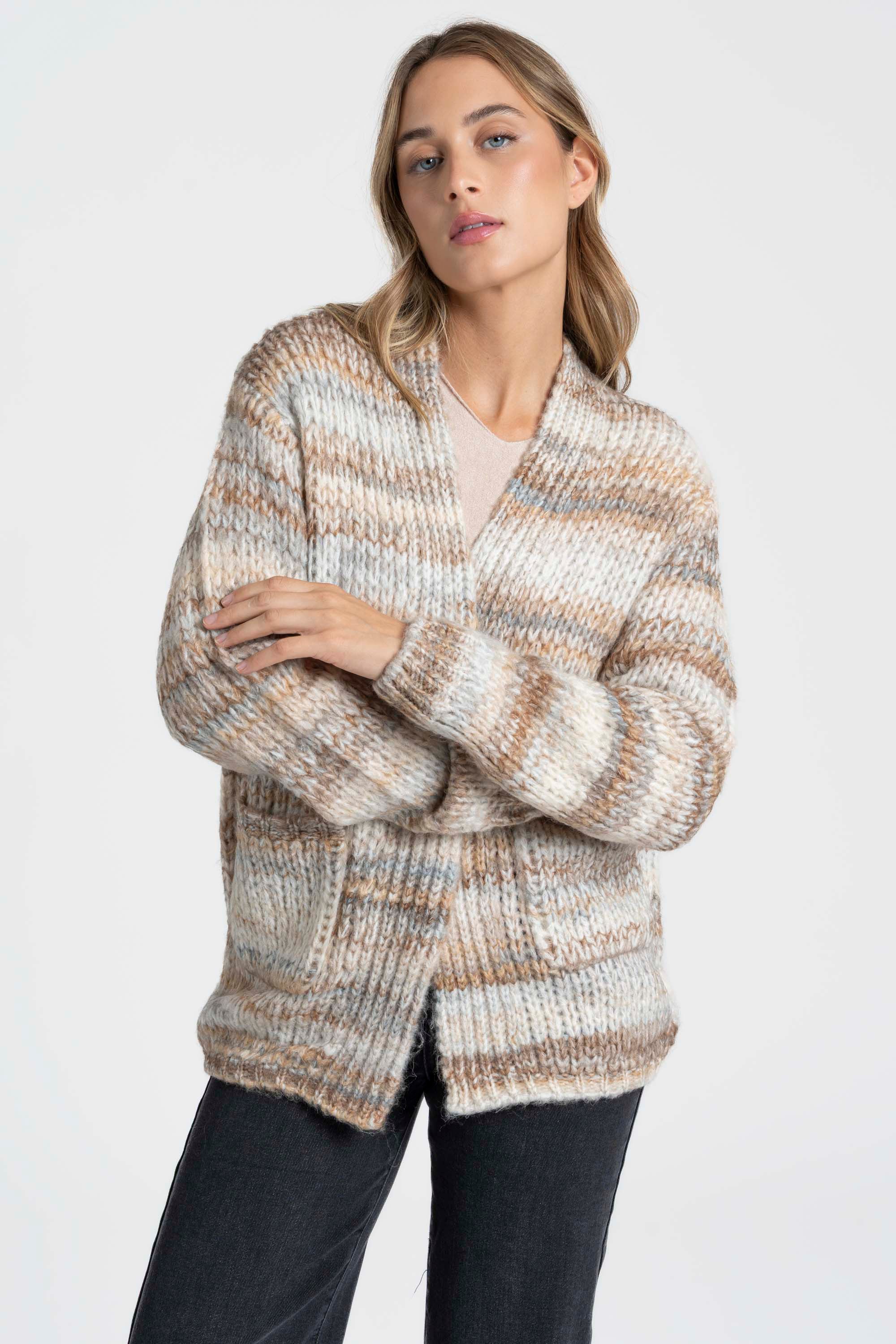 Une femme en tenue casual portant un cardigan court en maille beige et crème. Ce cardigan court femme en maille est parfait pour superposer.
