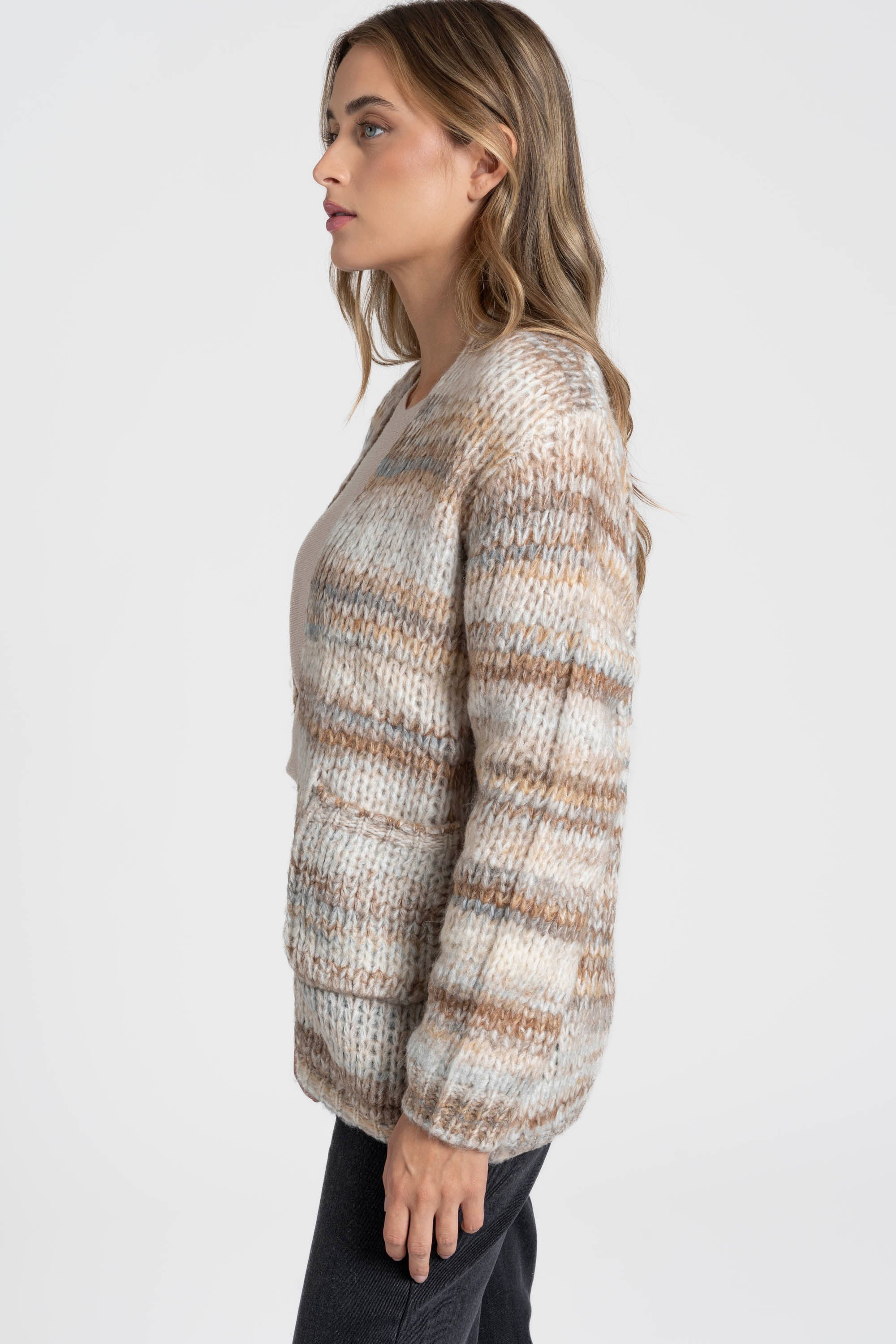 Profil d'une femme vêtue d'un cardigan court en maille beige, montrant la fluidité de la coupe. Ce cardigan court femme en maille est idéal pour un style décontracté.