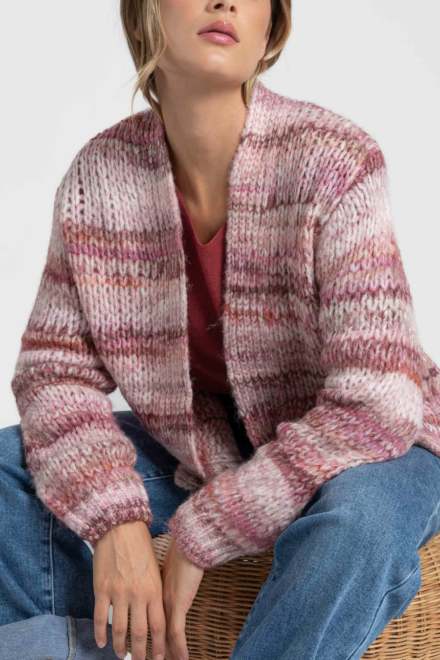 Gros plan sur une femme et son cardigan court en maille, montrant le motif rose et beige. Le cardigan court femme en maille dispose de poches pratiques.
