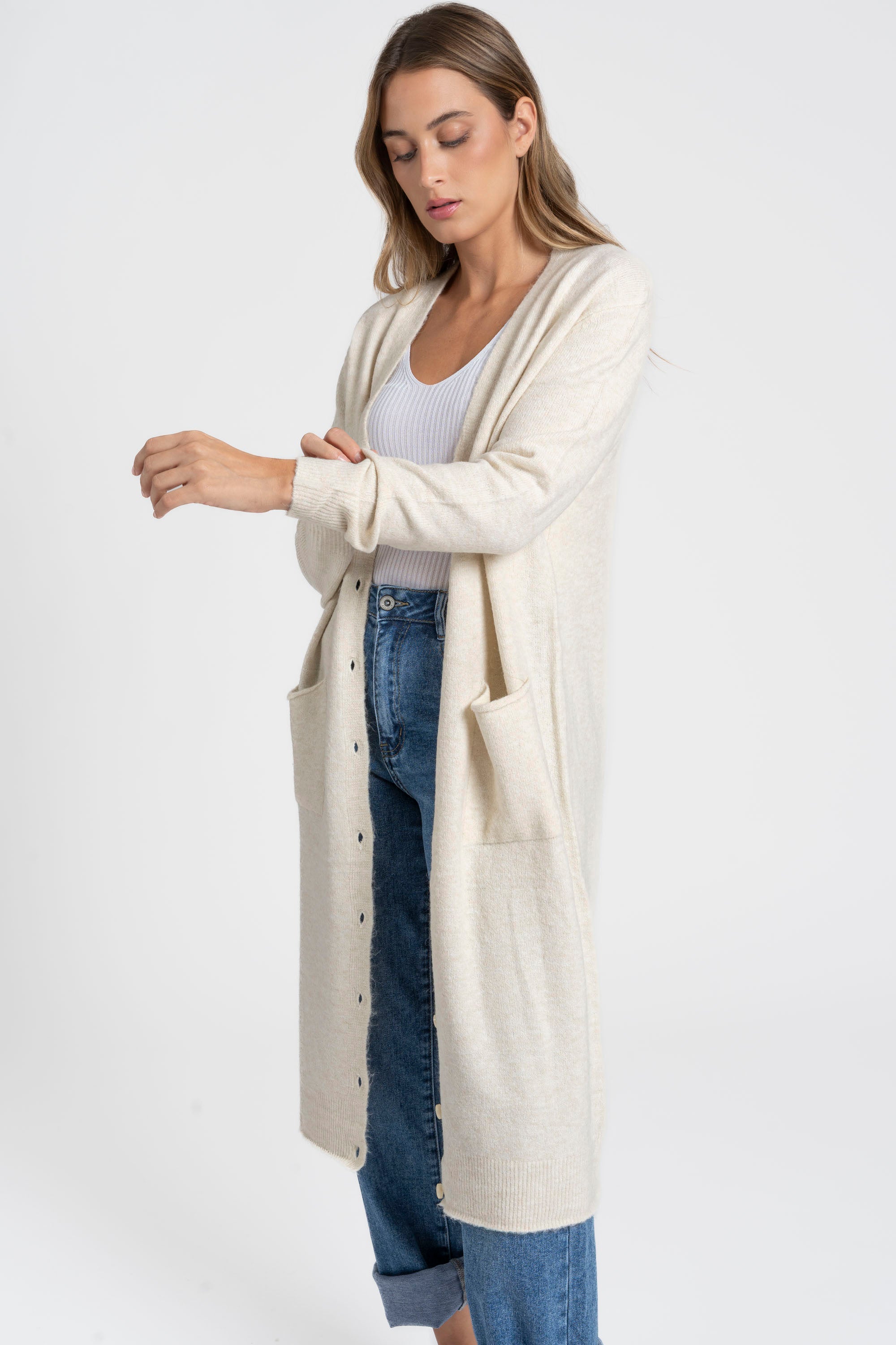 Modèle portant un cardigan long femme couleur beige, coupe droite en laine mélangée, avec des poches, idéal pour une tenue décontractée.