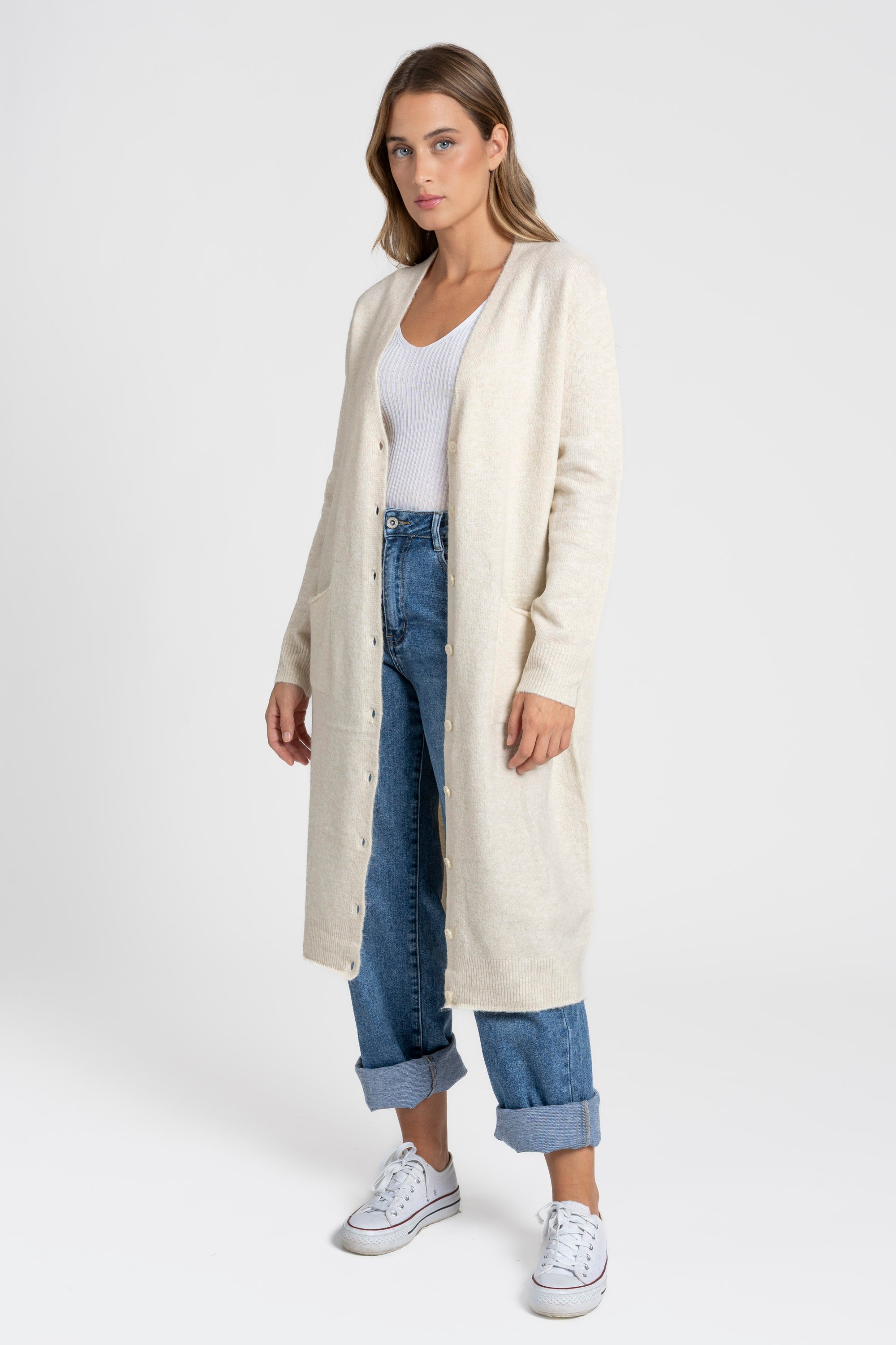 Femme affichant un cardigan long femme beige, avec une coupe droite et des boutons, parfait pour un look moderne et comfortable.
