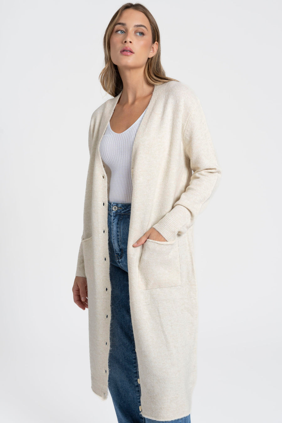 Détail d'un cardigan long femme en laine mélangée beige, mettant en valeur la coupe droite et les poches, un choix chic et pratique.
