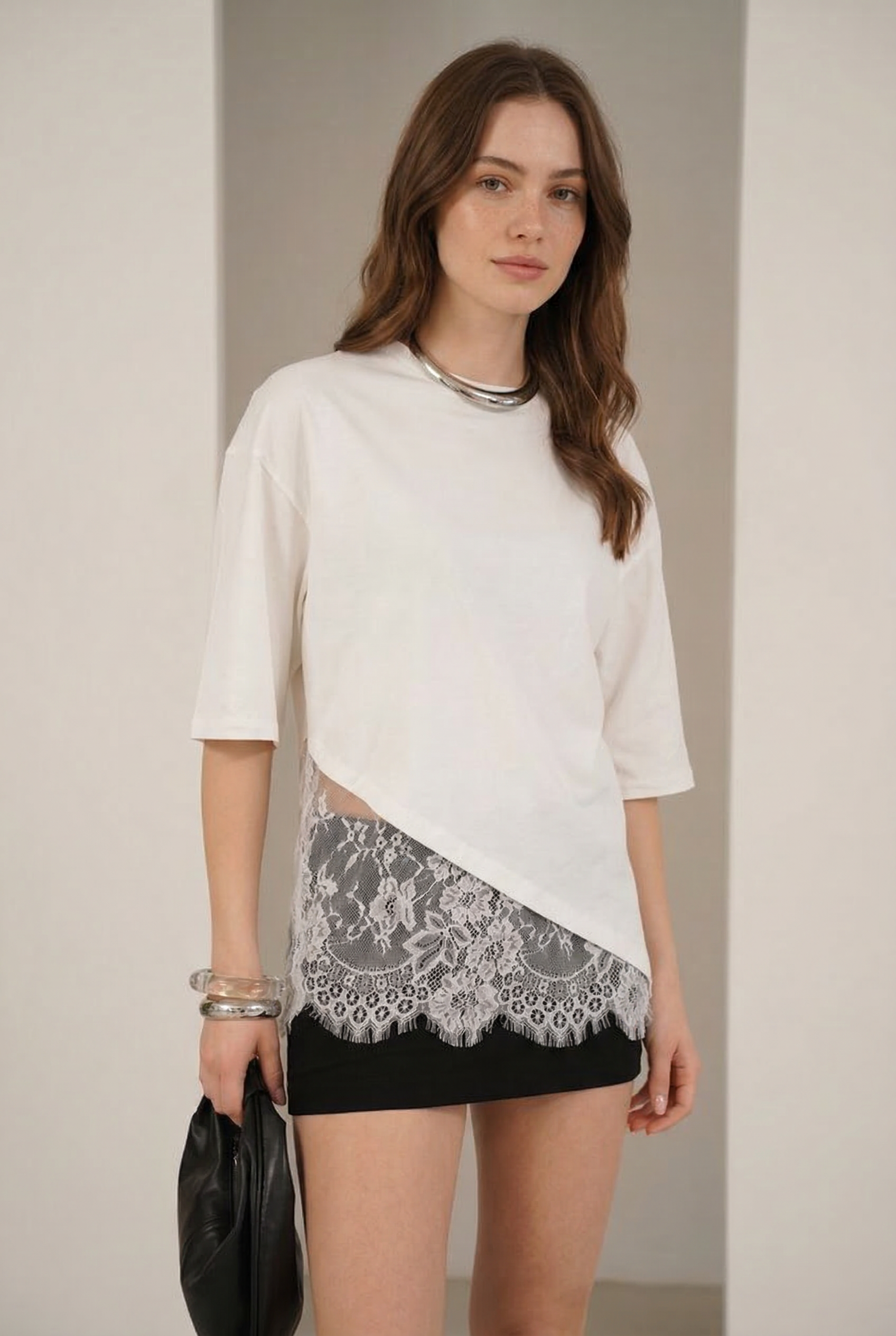 Femme portant un chemisier dentelle crème femme asymétrique en coton, mettant en valeur la dentelle avec un look moderne et élégant.