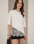 Femme portant un chemisier dentelle crème femme asymétrique en coton, mettant en valeur la dentelle avec un look moderne et élégant.