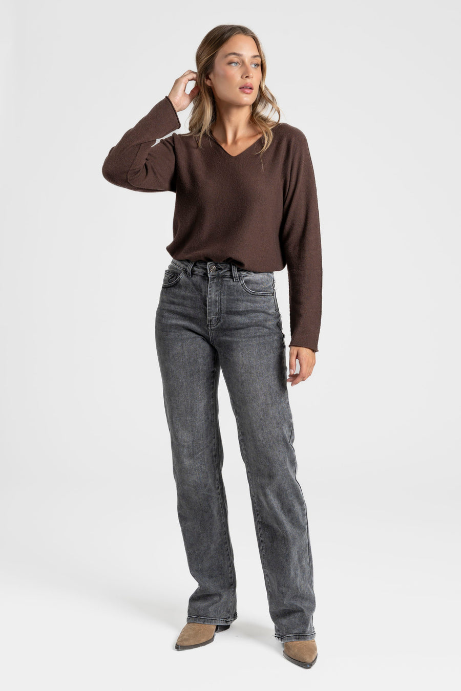 Pull fin col V femme en couleur marron, porté avec un jean noir pour un look chic et décontracté.