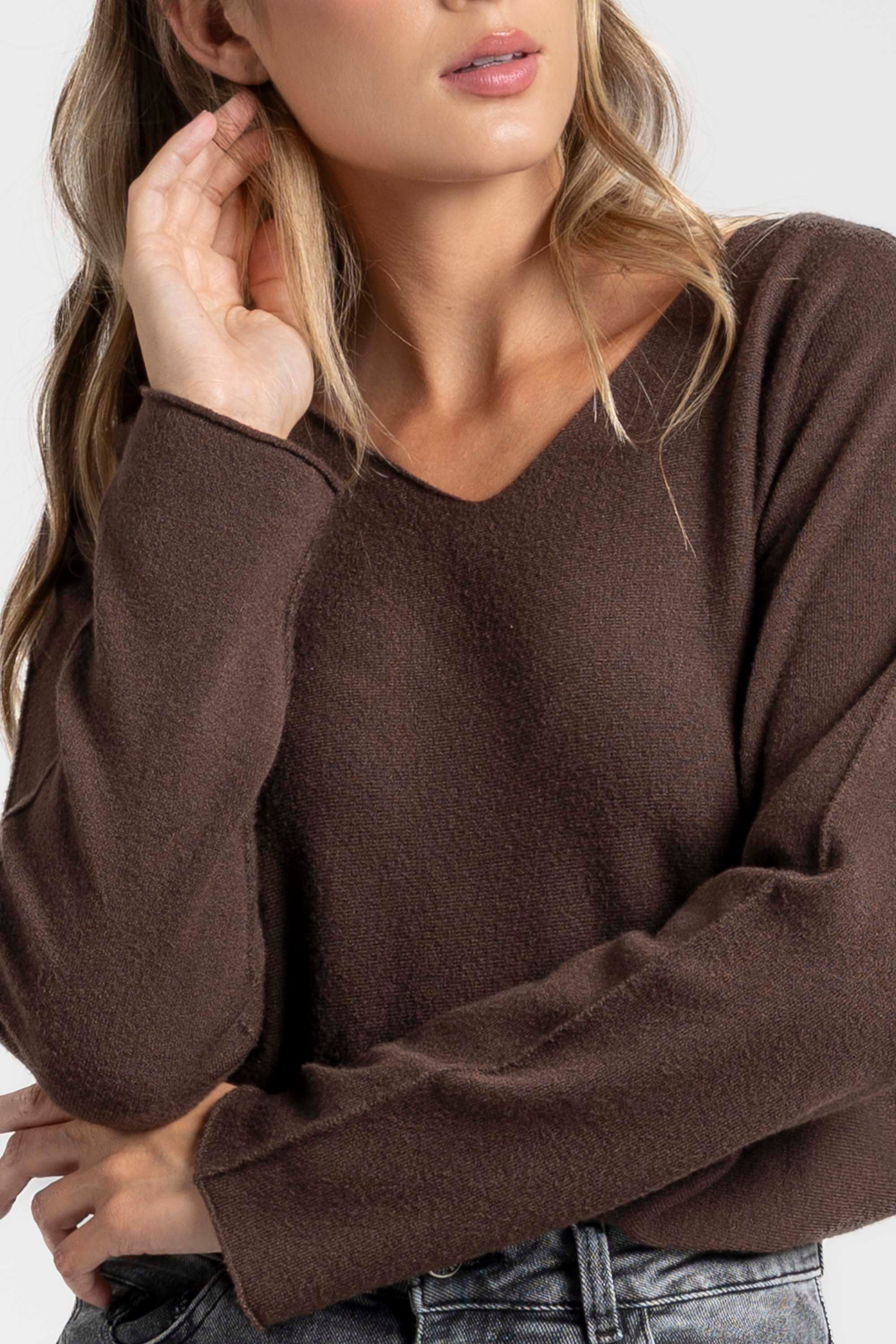 Pull fin col V femme en maille douce, porté avec une touche élégante, parfait pour un look décontracté.