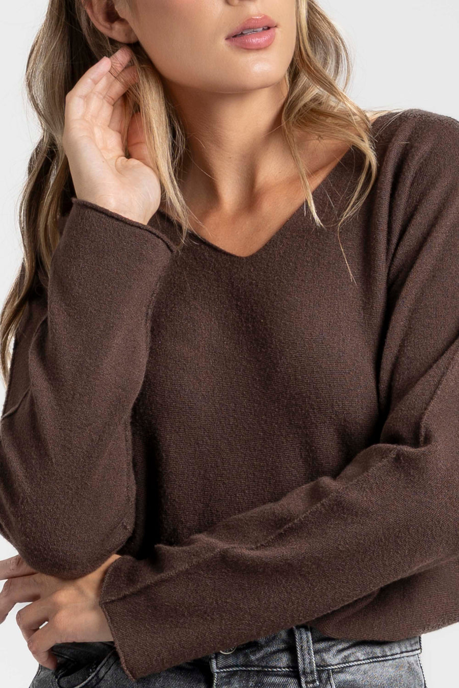 Pull fin col V femme en maille douce, porté avec une touche élégante, parfait pour un look décontracté.