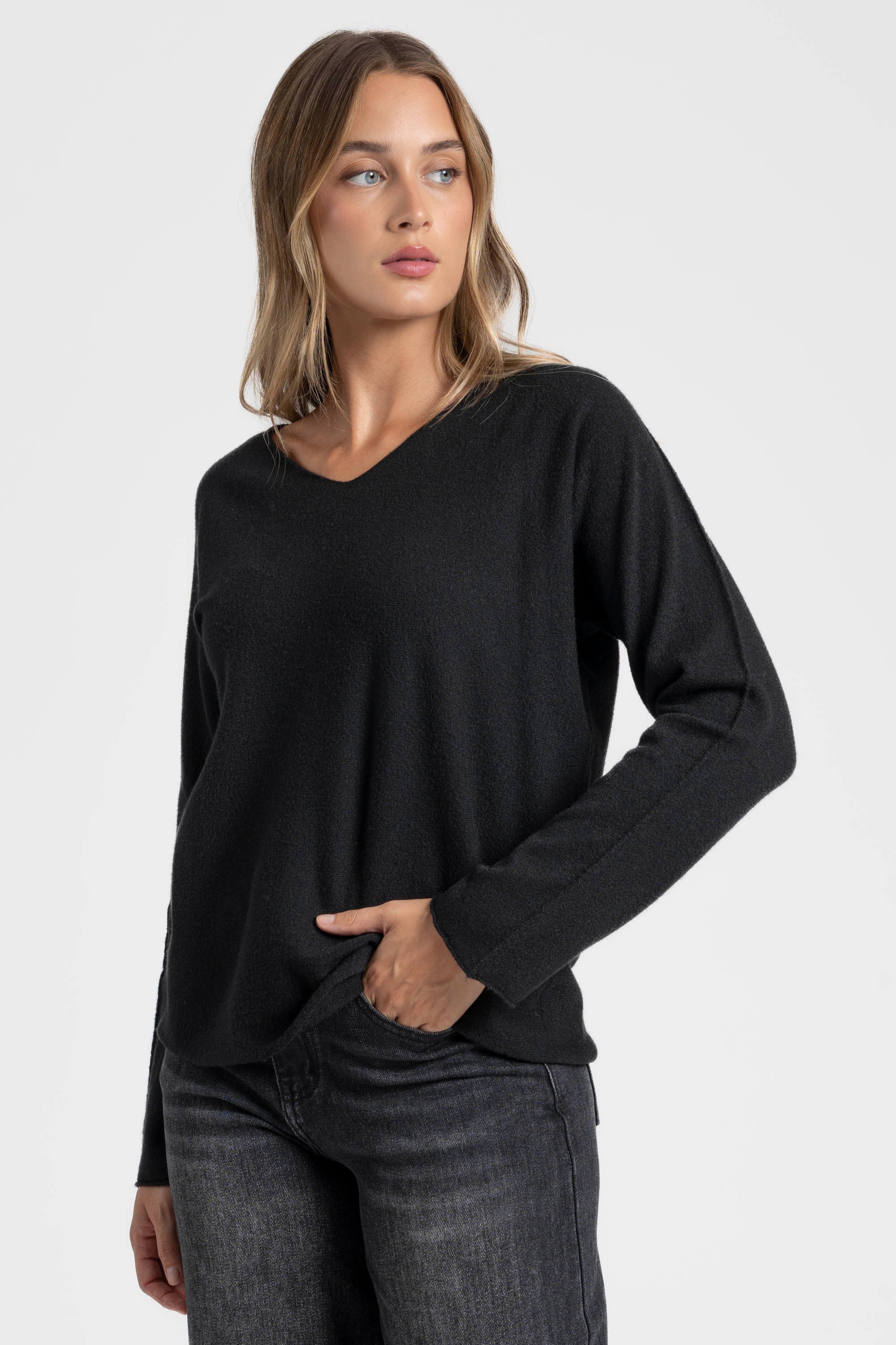 Pull col V femme couleur noir, associé à un jean, ajoutant une touche vibrante à la garde-robe.