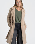 Manteau croisé femme beige, avec un pantalon stylé, parfait pour un look de mi-saison.