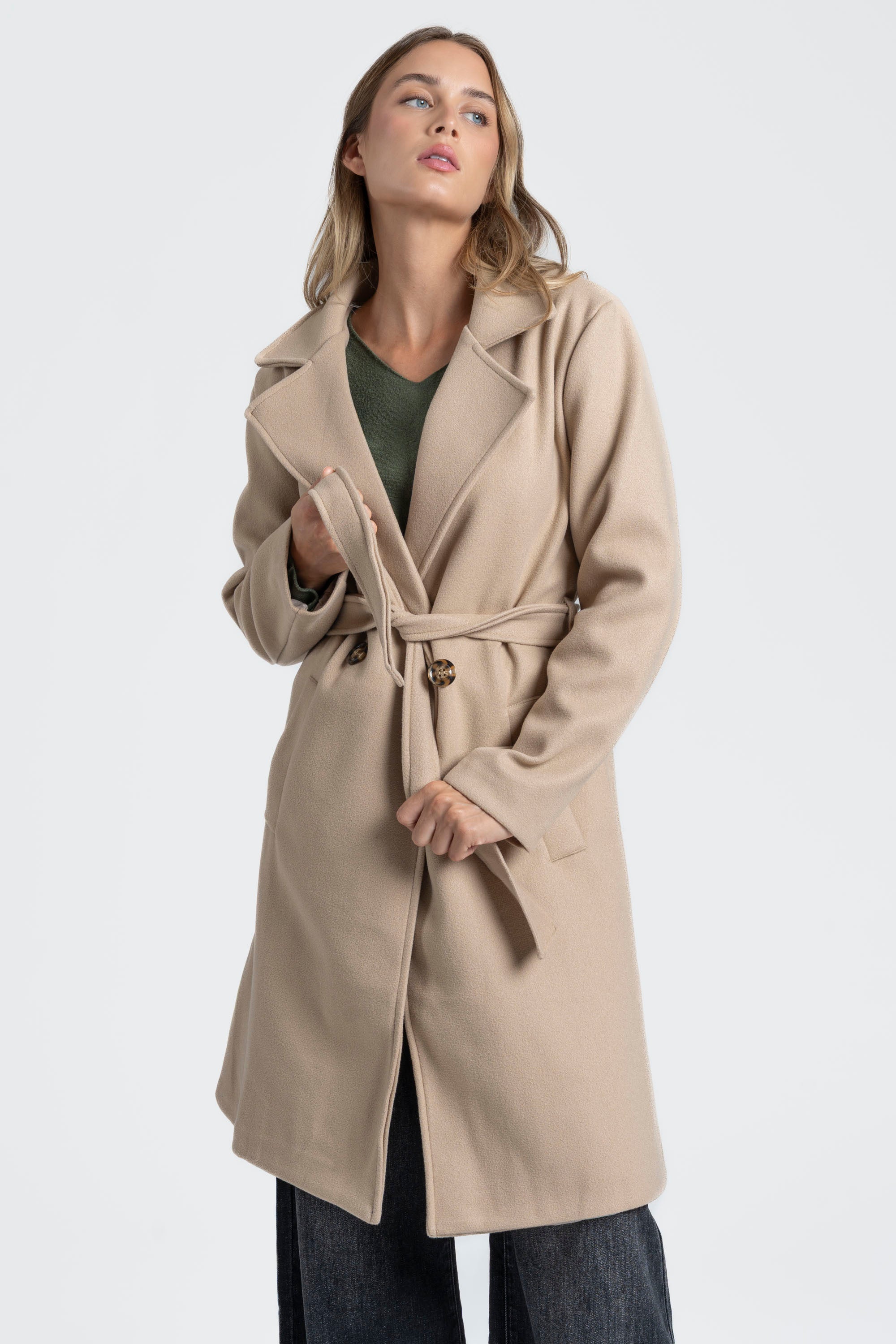 Détail du manteau croisé femme beige, soulignant la ceinture et les boutons élégants.