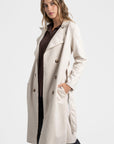 Trench femme ceinture beige de face, mettant en avant sa finition soignée et ses poches.