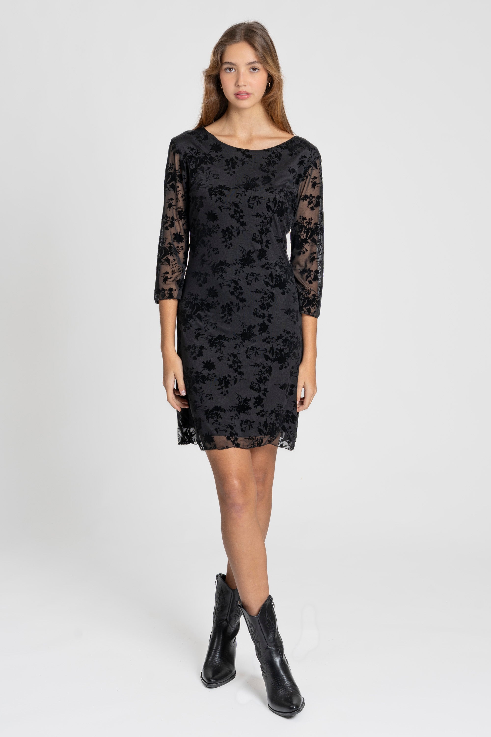 Femme portant une robe courte dentelle chic manches 3/4 noire, mettant en avant la sophistication de son motif et sa coupe flatteuse. Idéale pour toutes les occasions, robe courte dentelle.