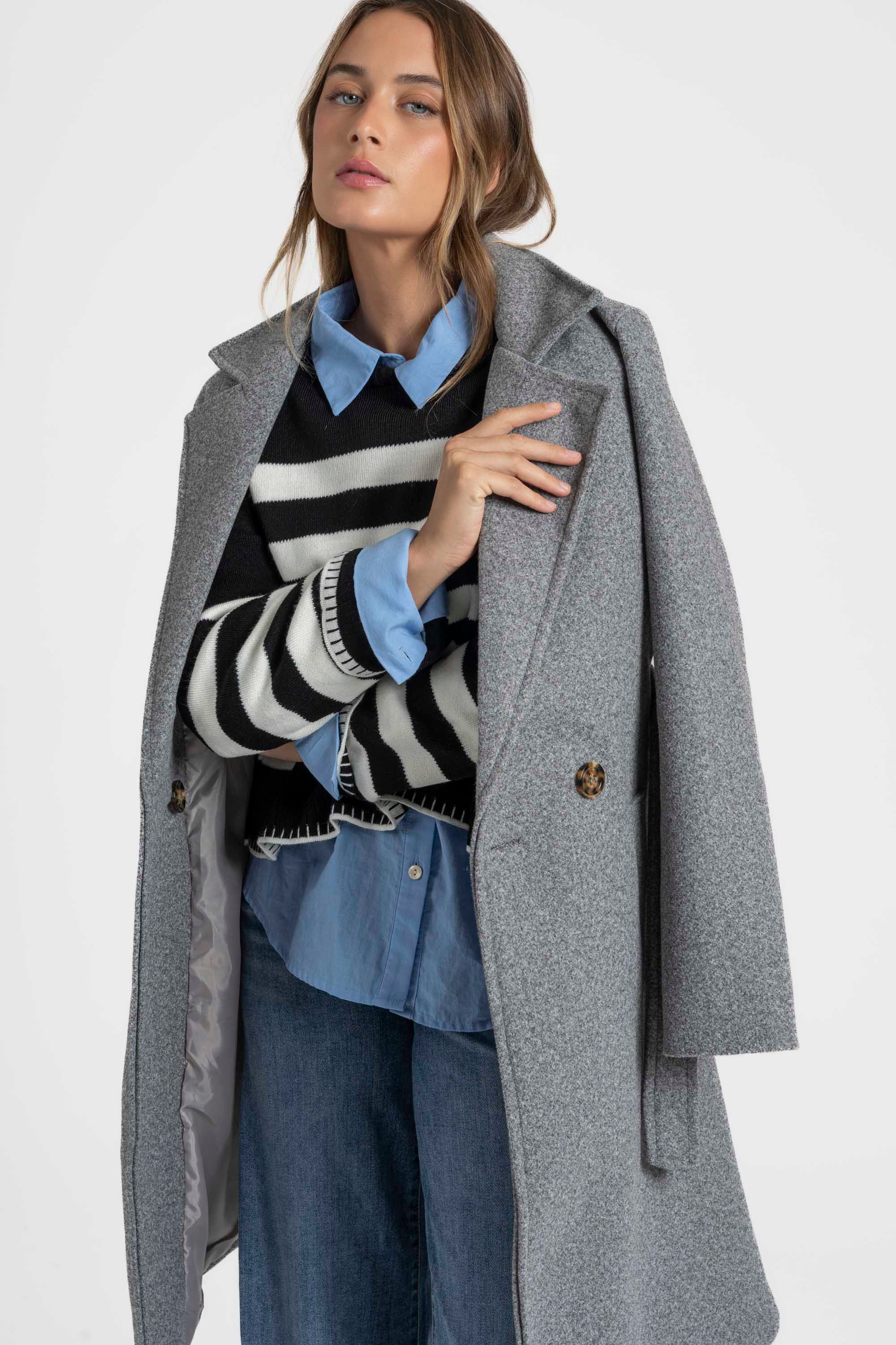 Manteau croisé femme en gris, détaillant la coupe droite et la ceinture, idéal pour une silhouette élégante.