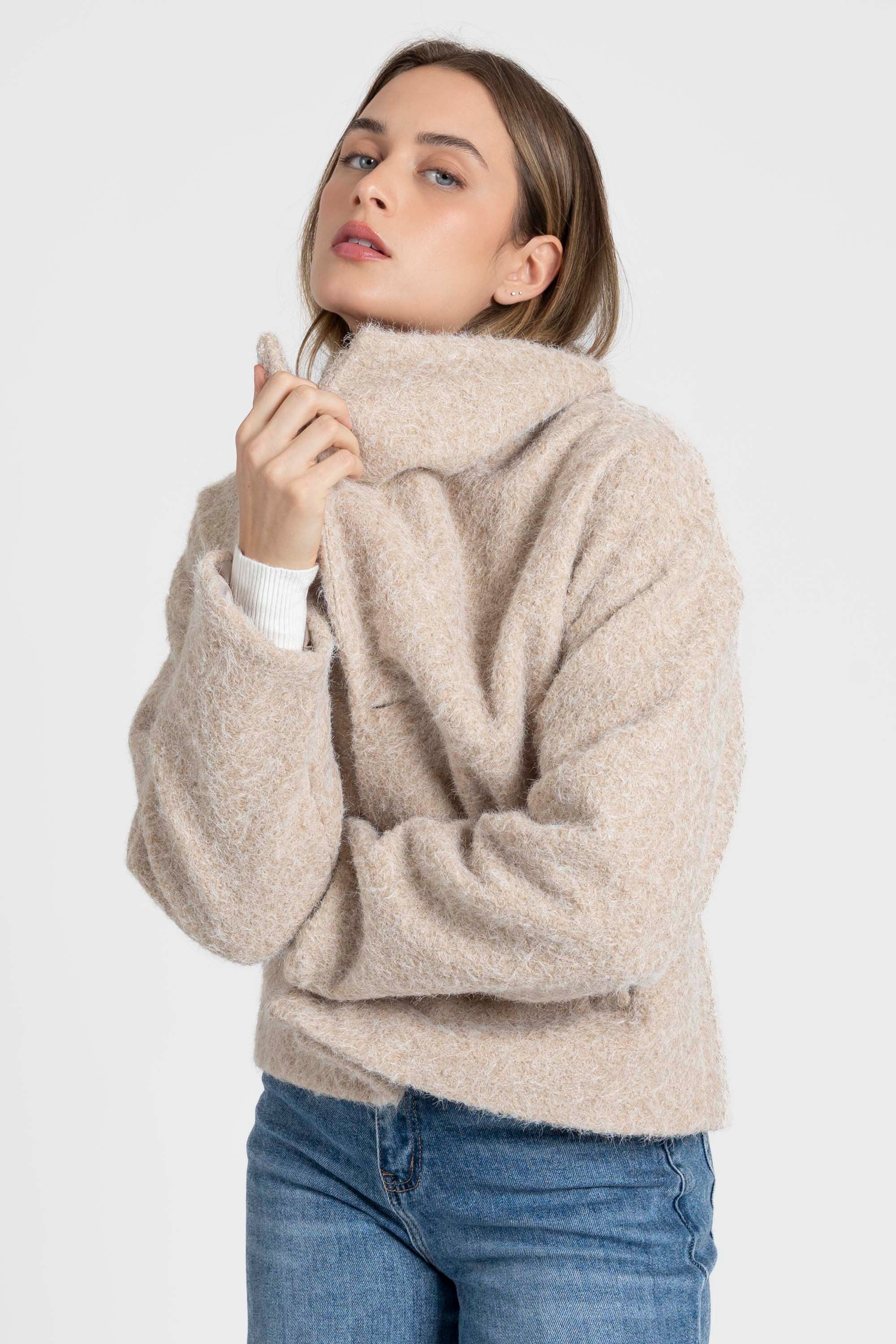 Femme ajustant sa veste courte effet poil doublée col à revers, un choix élégant pour une journée stylée. Veste courte femme.