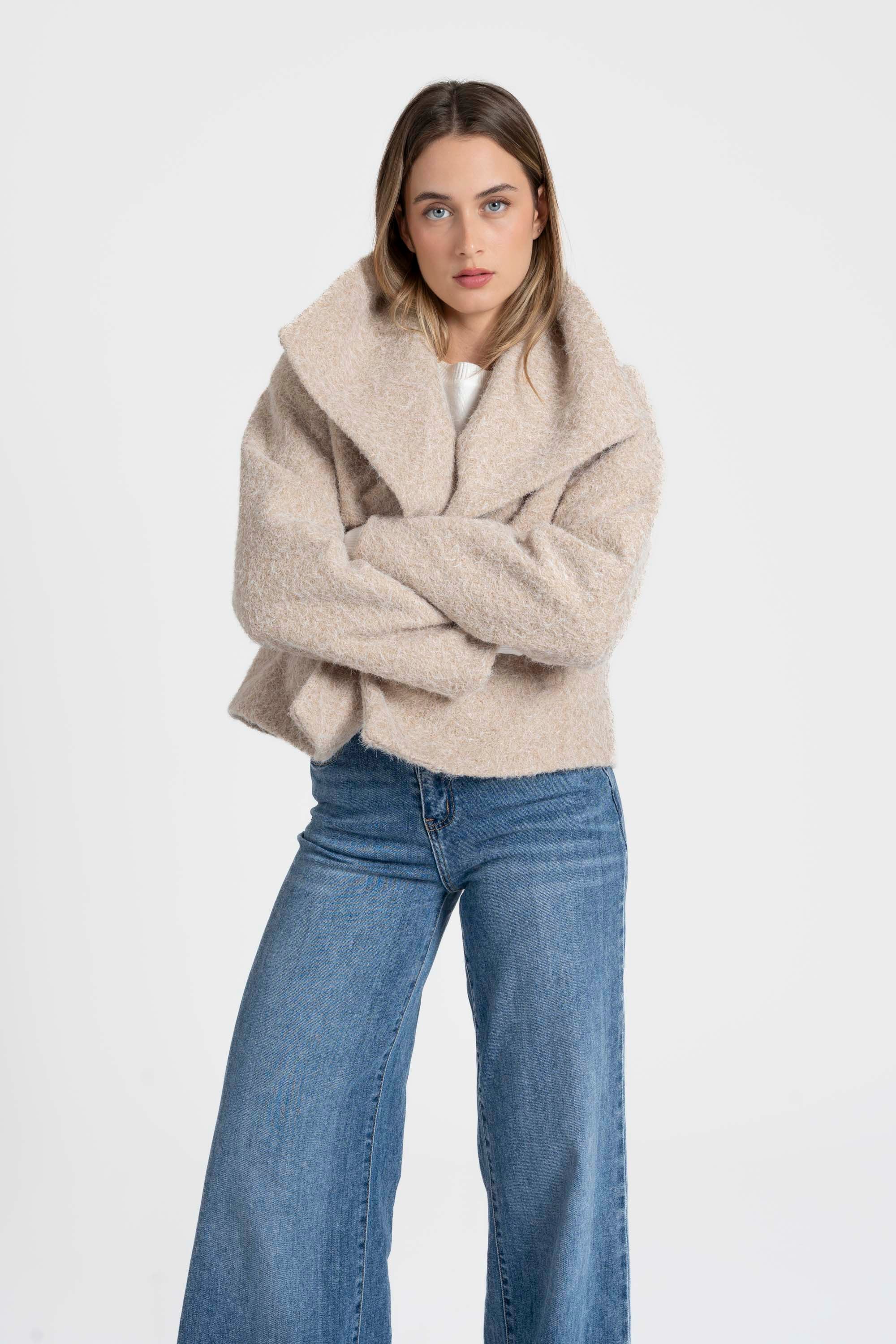 Femme posant dans une veste courte effet poil doublée col à revers, assortie avec un jean, pour une allure élégante. Veste courte femme.