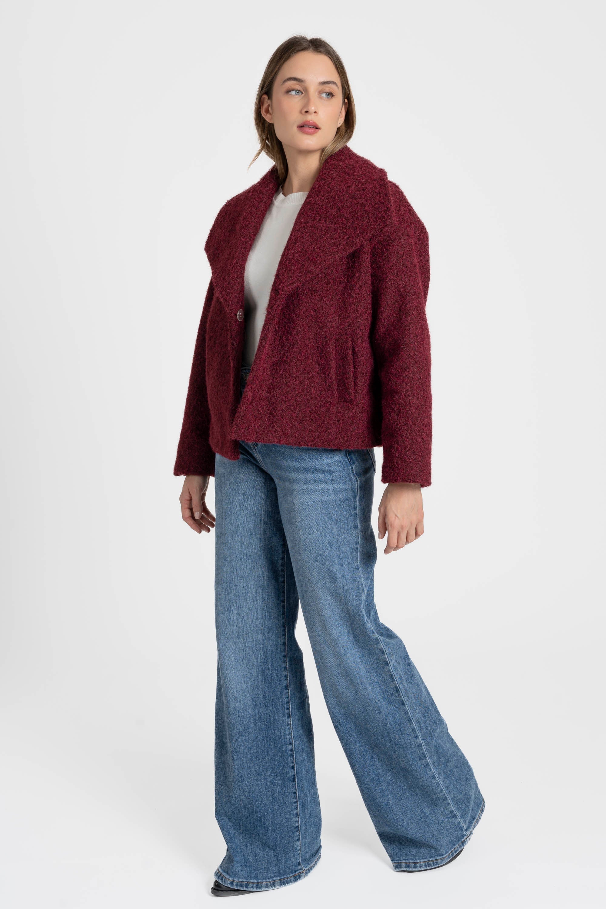 Femme posant dans une veste courte effet poil doublée col à revers rouge, pour une silhouette chic et stylée. Veste courte femme.