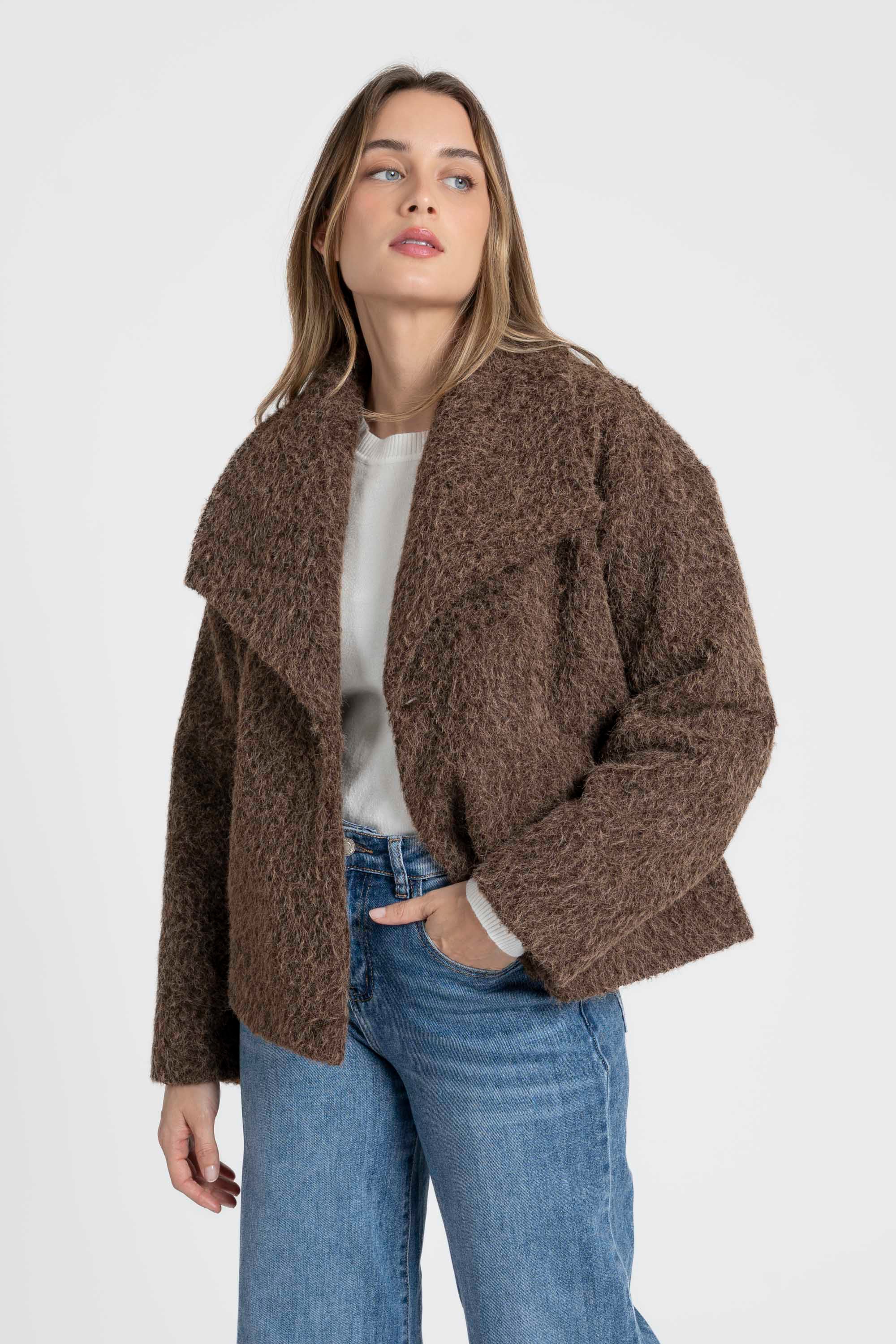 Femme portant une veste courte effet poil doublée col à revers, mise en valeur avec un jean, idéale pour un look élégant et décontracté. Veste courte femme.