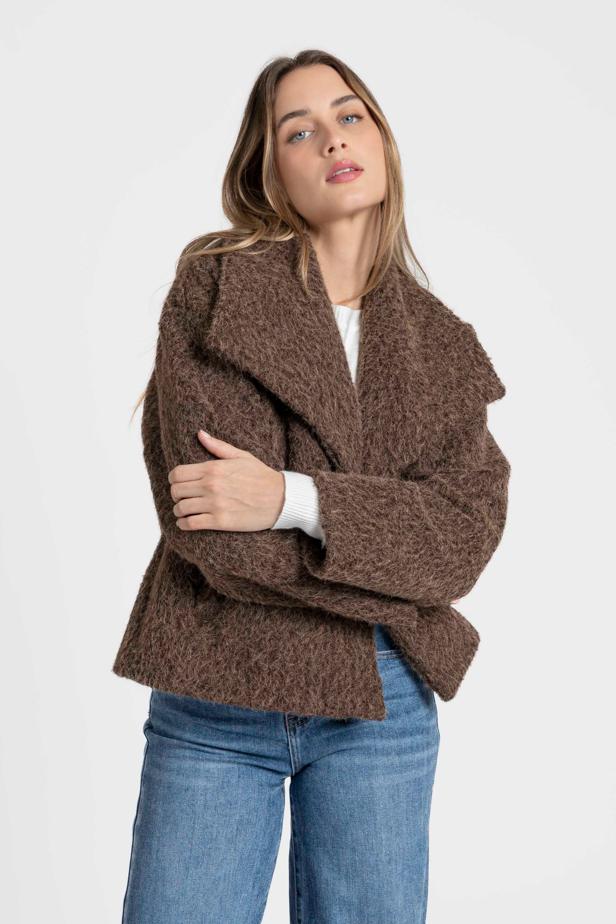 Femme posant dans une veste courte effet poil doublée col à revers, mettant en avant son style avec un look casual chic. Veste courte femme.